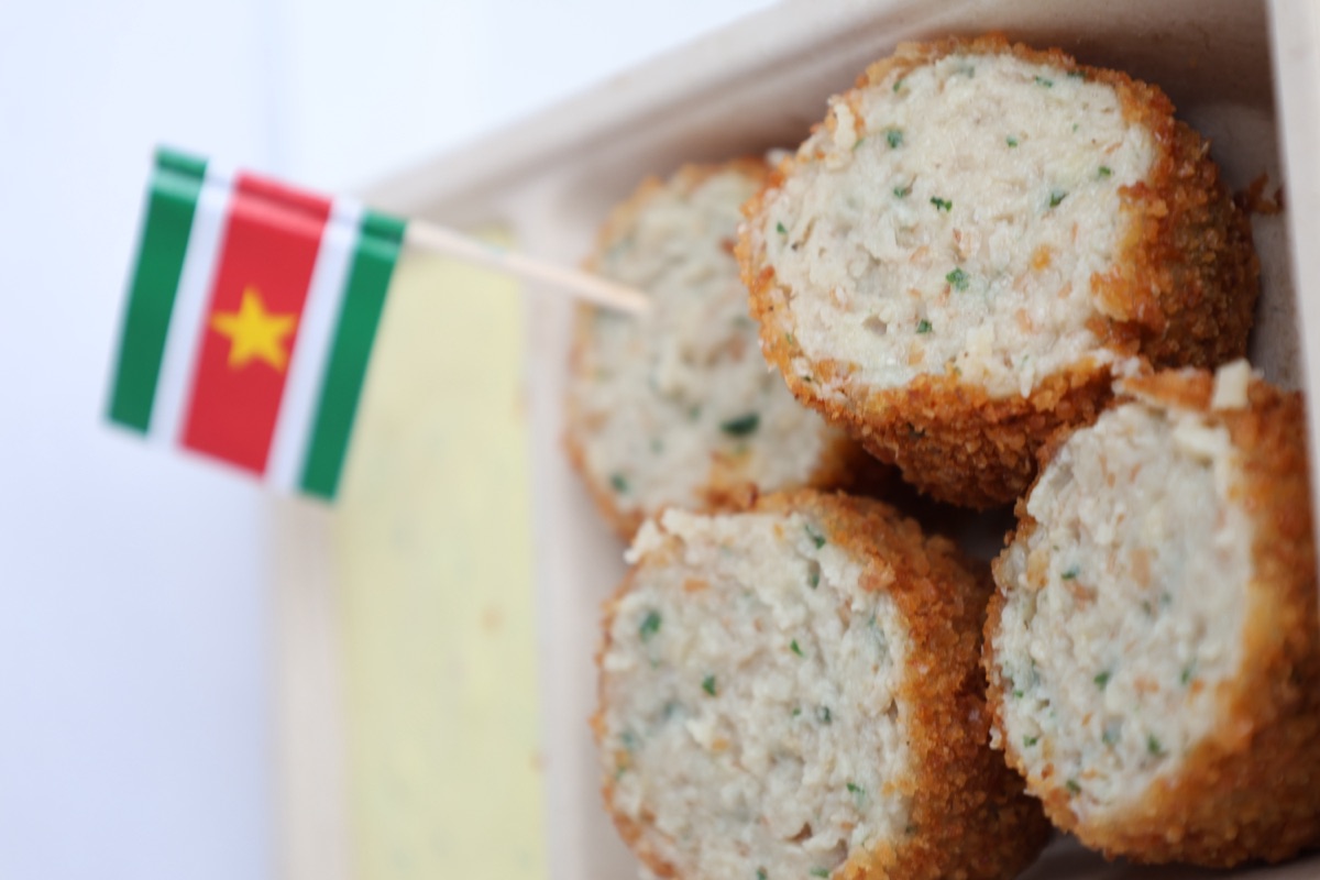 Portie crispy vleesworst in een bakje met een Surinaamse vlag